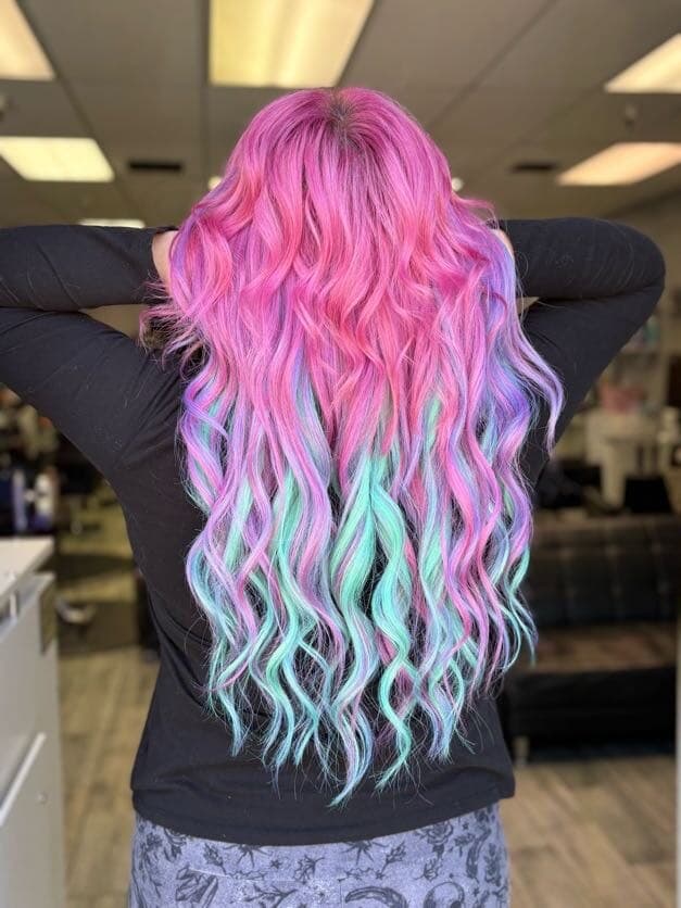 Long wavy hair extensions in pink, purple, and teal